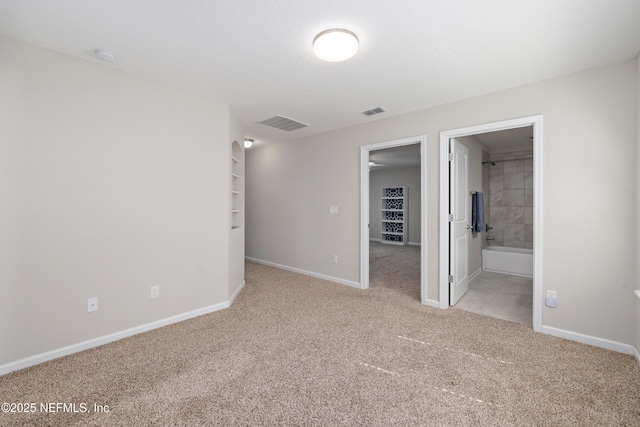 unfurnished bedroom with ensuite bathroom and light carpet