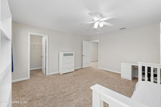 unfurnished bedroom featuring a spacious closet, light carpet, ceiling fan, and a closet