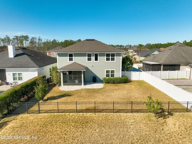 rear view of house with a yard, a patio, a sunroom, a residential view, and a fenced backyard