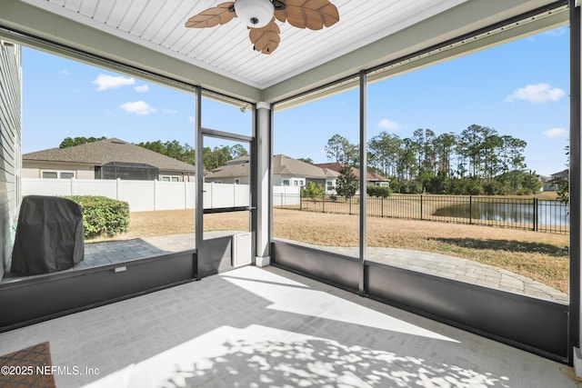 sunroom / solarium with a water view and ceiling fan