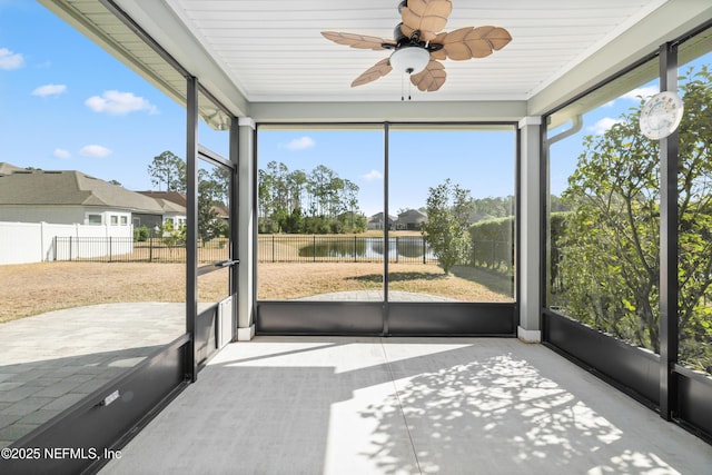 unfurnished sunroom featuring plenty of natural light, a water view, and a ceiling fan