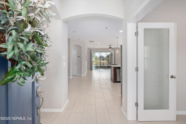 hall featuring arched walkways, baseboards, and recessed lighting