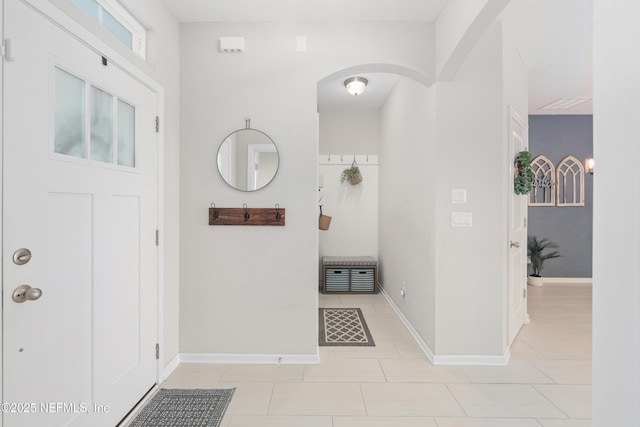 foyer entrance with arched walkways, heating unit, baseboards, and light tile patterned floors