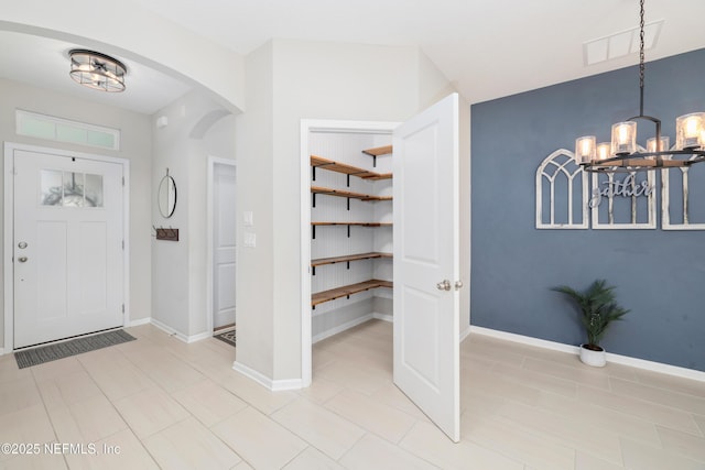 foyer with baseboards, visible vents, arched walkways, and a notable chandelier