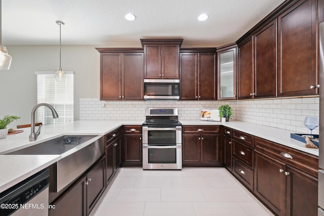 kitchen with decorative backsplash, appliances with stainless steel finishes, pendant lighting, a sink, and recessed lighting