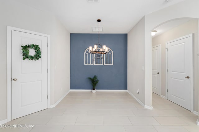 unfurnished dining area featuring arched walkways, visible vents, baseboards, and an inviting chandelier