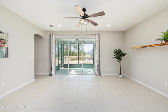 unfurnished room featuring arched walkways, ceiling fan, visible vents, and baseboards