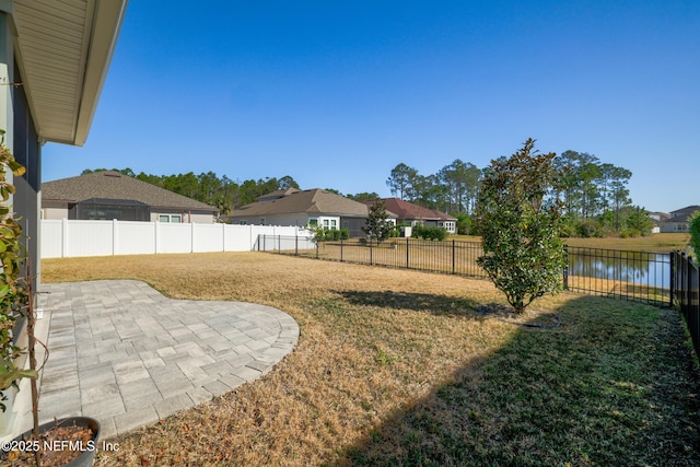 view of yard featuring a patio, a water view, and a fenced backyard