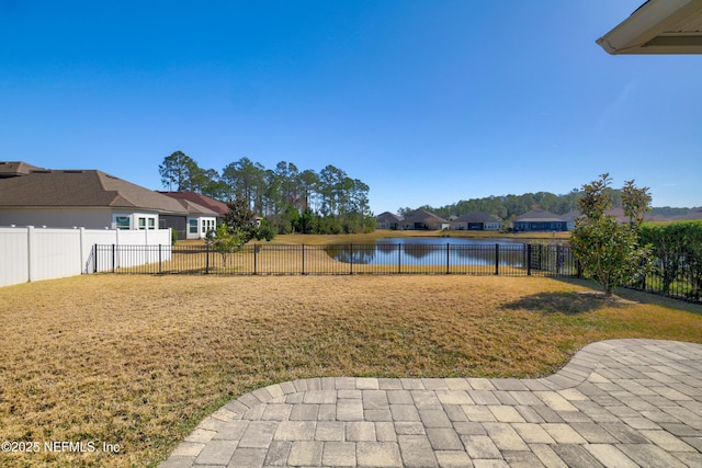 view of yard featuring a patio area, a water view, and a fenced backyard