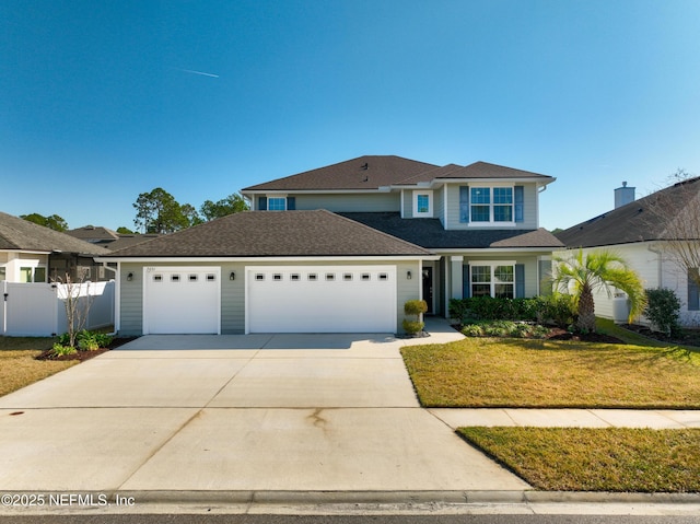 traditional-style house featuring a garage, concrete driveway, fence, and a front lawn