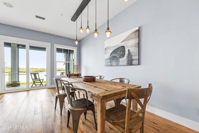 dining room featuring a water view, vaulted ceiling, and hardwood / wood-style floors