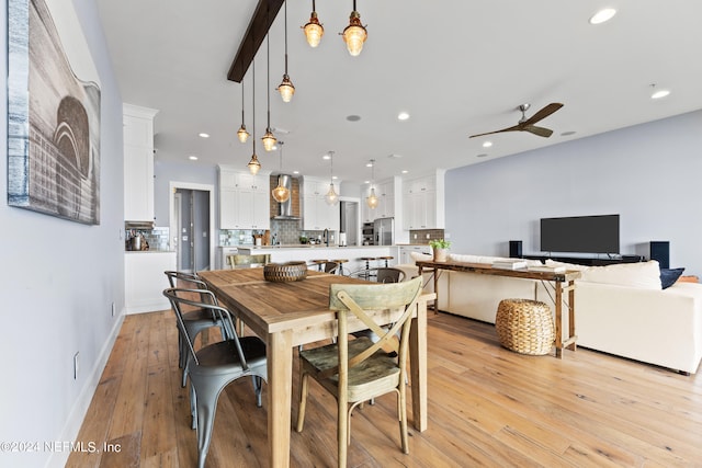 dining room with beam ceiling, ceiling fan, and light wood-type flooring