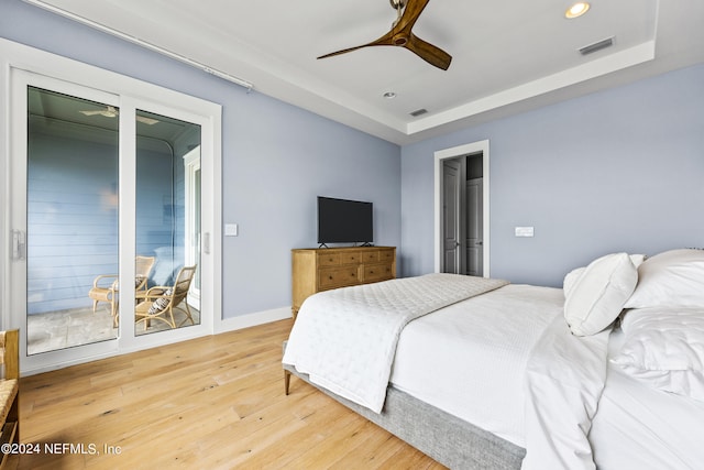 bedroom with ceiling fan, a raised ceiling, and hardwood / wood-style floors