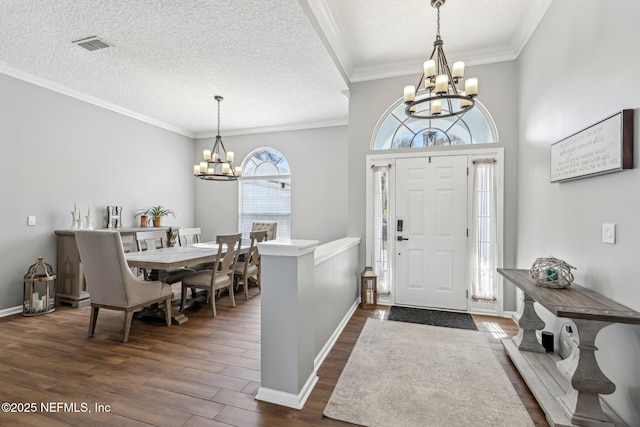 foyer entrance with an inviting chandelier, crown molding, dark wood-type flooring, and a textured ceiling