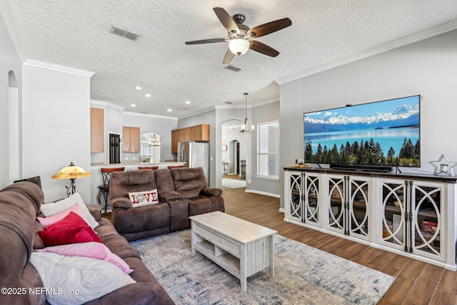 living room with hardwood / wood-style floors, a textured ceiling, ornamental molding, and ceiling fan