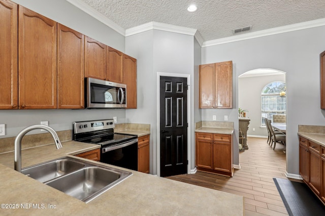 kitchen featuring sink, hardwood / wood-style flooring, stainless steel appliances, ornamental molding, and a textured ceiling