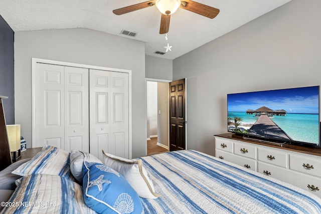 bedroom featuring ceiling fan, vaulted ceiling, a closet, and a textured ceiling