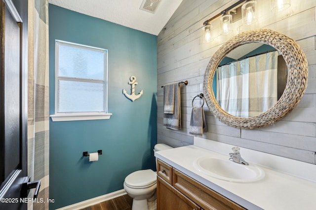 bathroom with vanity, lofted ceiling, toilet, and wood walls