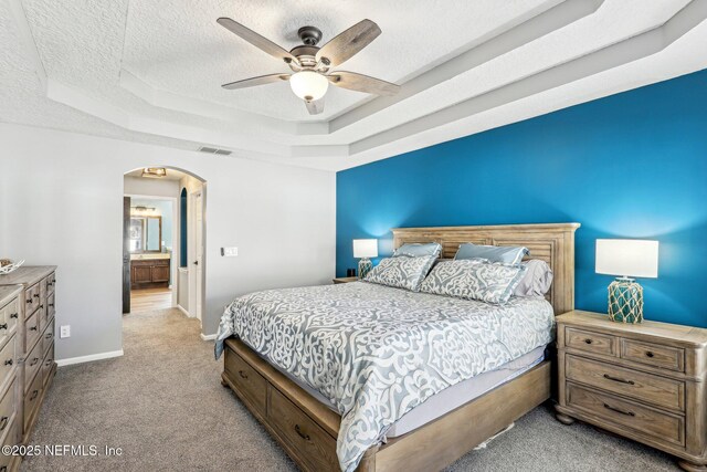 carpeted bedroom with ceiling fan, a raised ceiling, and a textured ceiling