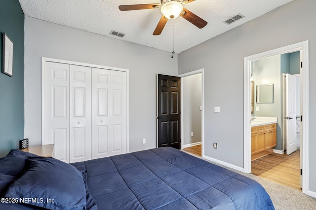 bedroom featuring ensuite bathroom, wood-type flooring, a textured ceiling, a closet, and ceiling fan