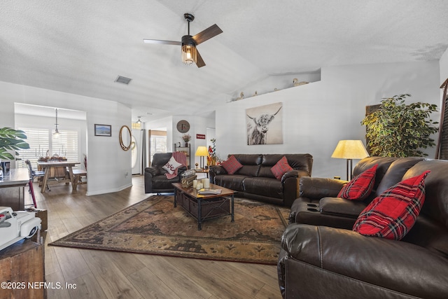 living room with vaulted ceiling, ceiling fan, hardwood / wood-style floors, and a textured ceiling