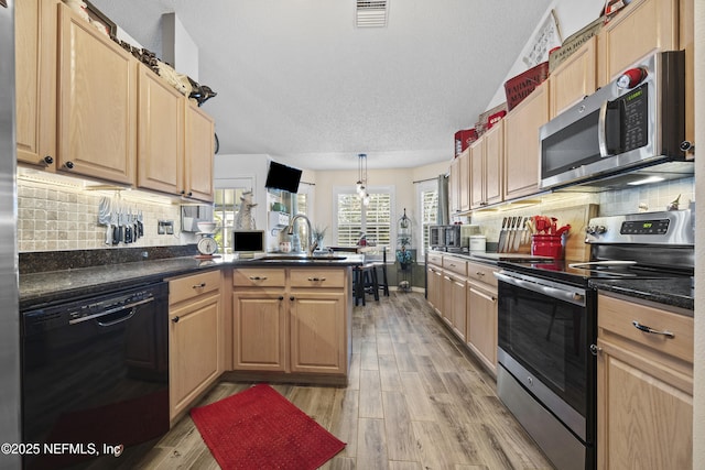 kitchen featuring sink, decorative light fixtures, light wood-type flooring, and appliances with stainless steel finishes