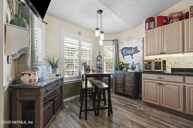 kitchen featuring dark wood-type flooring, pendant lighting, a textured ceiling, and decorative backsplash