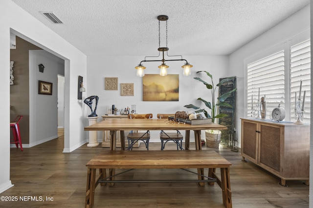 dining area featuring a textured ceiling and dark hardwood / wood-style flooring