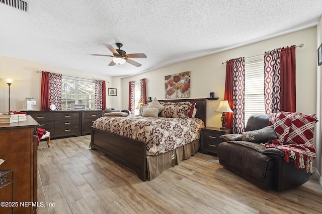 bedroom with ceiling fan, a textured ceiling, and light wood-type flooring