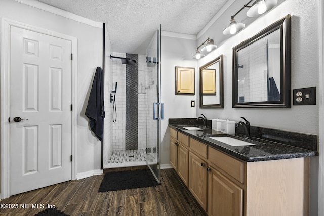 bathroom featuring vanity, hardwood / wood-style flooring, a shower with door, and a textured ceiling