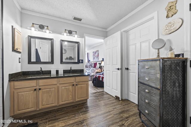 bathroom featuring vanity, crown molding, and a textured ceiling