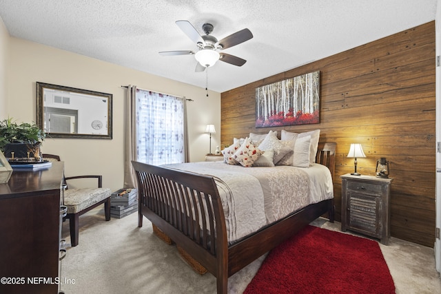 carpeted bedroom featuring ceiling fan, wooden walls, and a textured ceiling