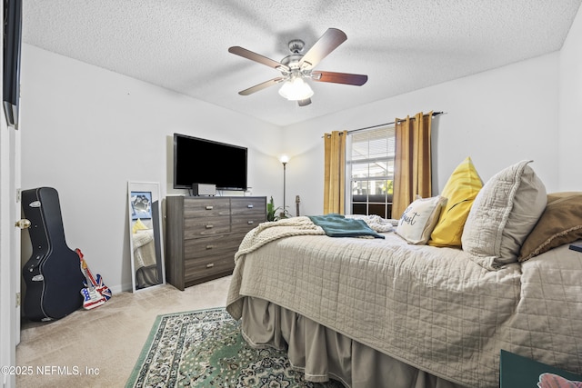 bedroom with ceiling fan, light carpet, and a textured ceiling