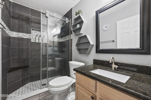 bathroom featuring vanity, a shower with door, toilet, and a textured ceiling