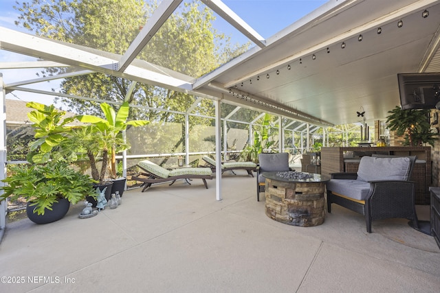 view of patio / terrace featuring a lanai and an outdoor living space with a fire pit