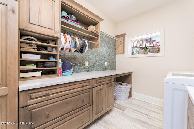 clothes washing area featuring washing machine and dryer, cabinet space, and baseboards