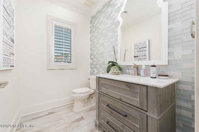 bathroom with toilet, crown molding, vanity, and baseboards