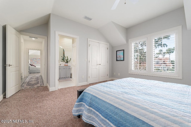 bedroom with lofted ceiling, ensuite bathroom, light colored carpet, visible vents, and baseboards