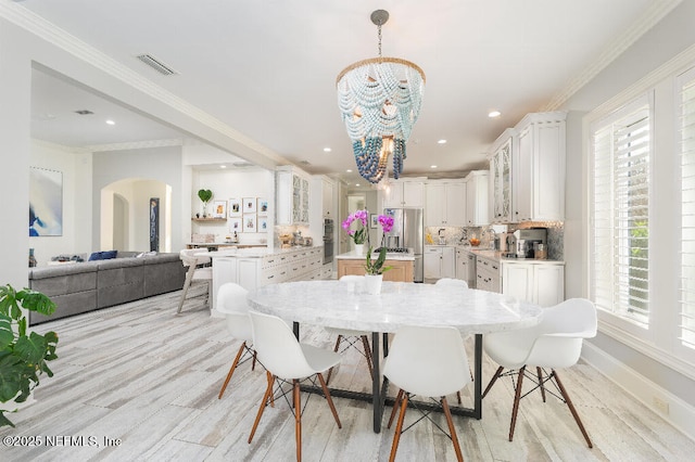 dining space featuring arched walkways, a notable chandelier, visible vents, and crown molding