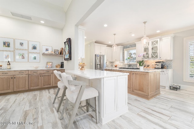 kitchen with a center island, decorative light fixtures, light countertops, glass insert cabinets, and stainless steel fridge with ice dispenser