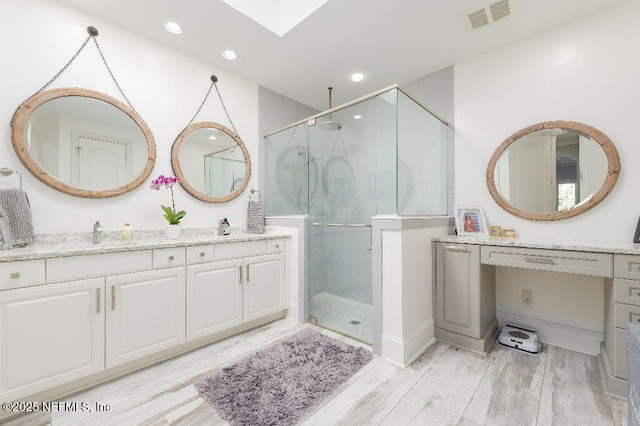 bathroom featuring a stall shower, visible vents, a sink, and wood finished floors