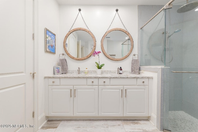 full bath with a stall shower, a sink, and double vanity