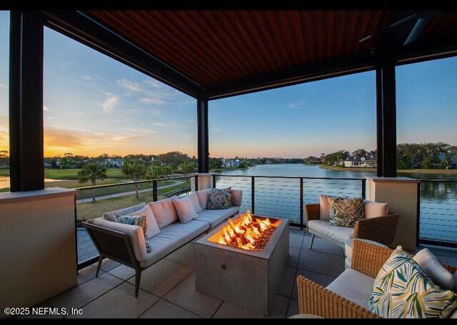 balcony with an outdoor living space with a fire pit and a water view