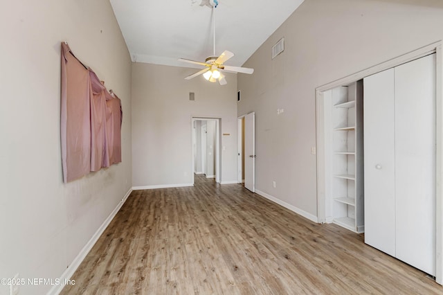 unfurnished bedroom with ceiling fan, a closet, high vaulted ceiling, and light hardwood / wood-style flooring