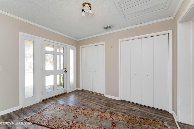 interior space featuring multiple closets, ornamental molding, dark wood-type flooring, and a textured ceiling