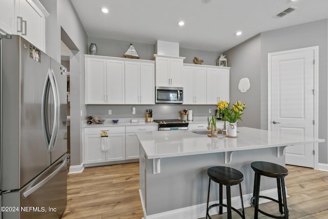 kitchen with white cabinetry, appliances with stainless steel finishes, and a kitchen island with sink