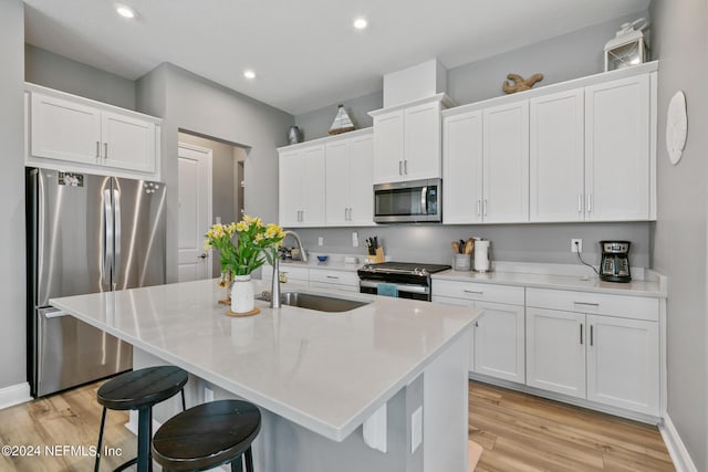 kitchen with a kitchen island with sink, sink, white cabinetry, and stainless steel appliances