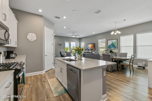 kitchen with white cabinetry, sink, stainless steel appliances, and an island with sink