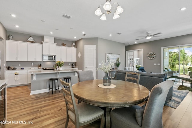 dining area featuring ceiling fan with notable chandelier and light hardwood / wood-style floors