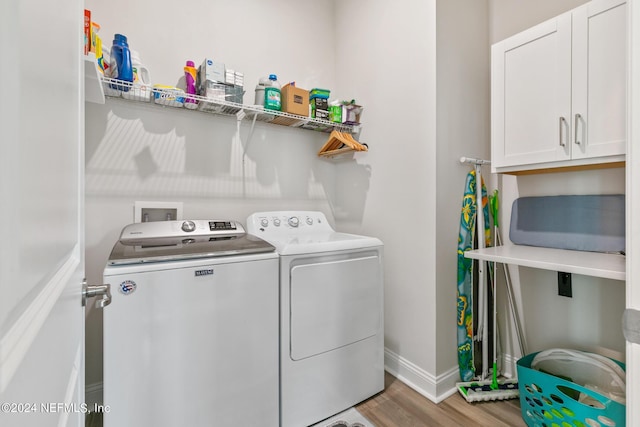 washroom with cabinets, washer and dryer, and light hardwood / wood-style flooring